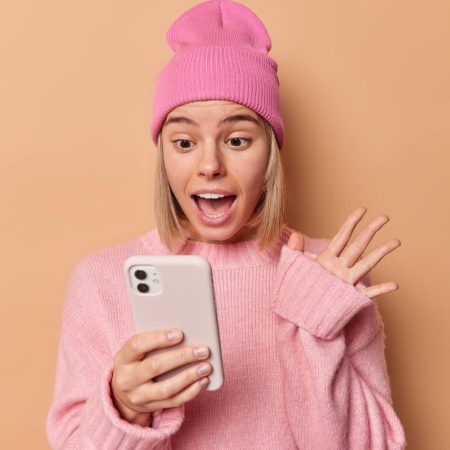 une jeune femme regarde son smartphone et semble interloquée